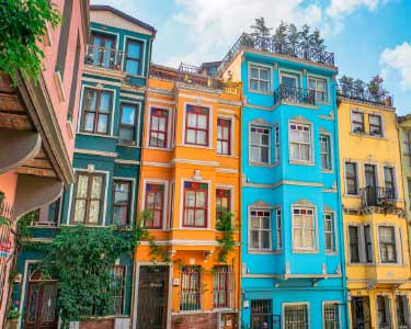İstanbul boya badana hizmetlerimiz için kullanılan görselde, İstanbul boyacı ustası tarafından dış cepheleri mavi, sarı ve pembe renklere boyanmış binalar var.