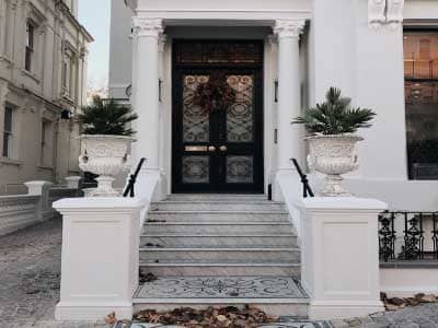 Kapı boyası renkleri kategorisi için kullanılan görselde, dış cephesi beyaz olan bir binanın siyah renkli demir kapısı var.