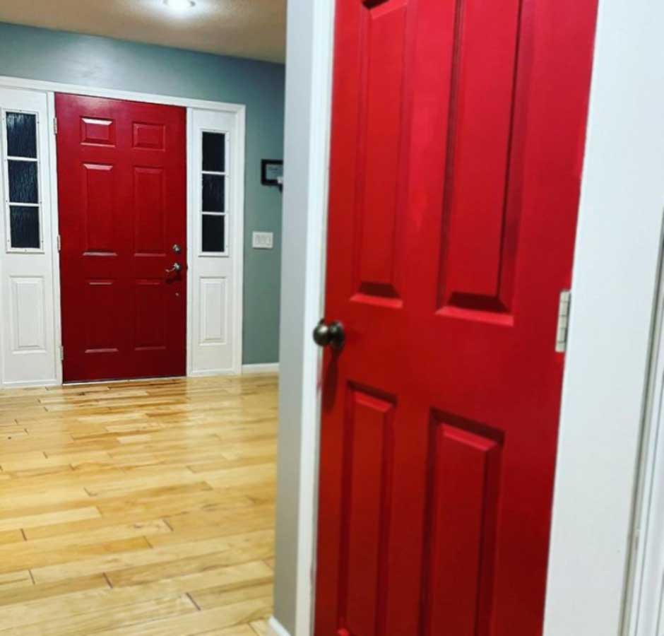 Görseldeki geniş salonda, iki adet koyu kırmızı ahşap kapı var.