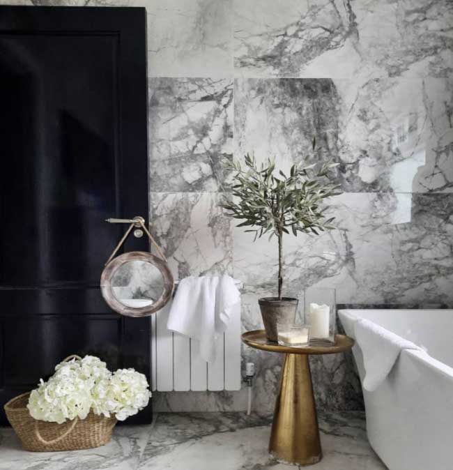 Görselde, ışıltılı modern bir banyoya açılan siyah renkli parlak bir ahşap kapı var.