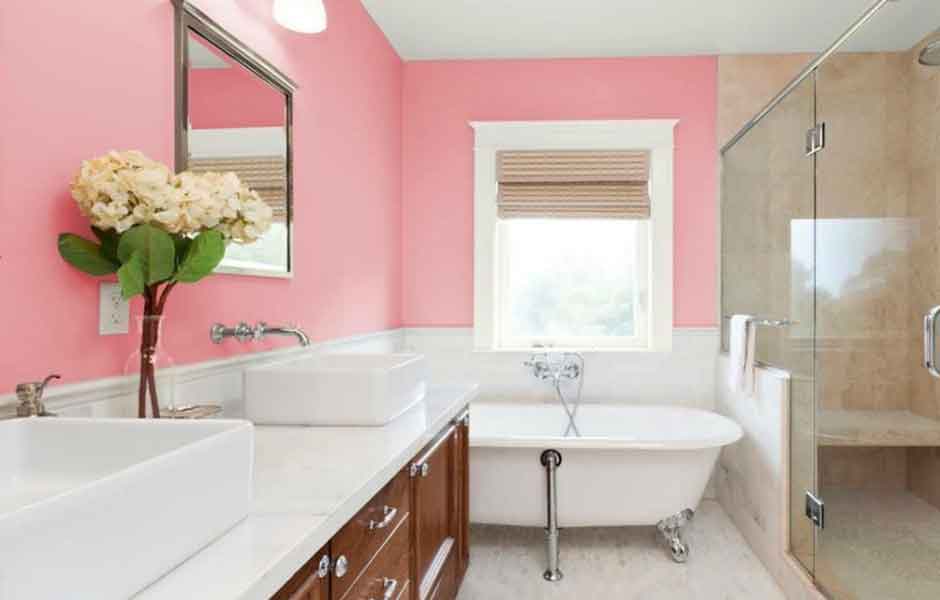 Görselde, pastel pembe renkli duvarlara sahip geniş bir banyo var.