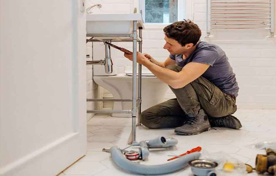 Görrselde, muslukçu banyo lavabosunun altından akan su sızıntısını gideriyor.