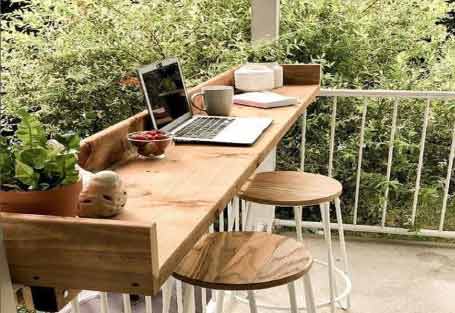 Görseldeki geniş balkonda, çalışma masası ve masanın üstünde bilgisayar var.