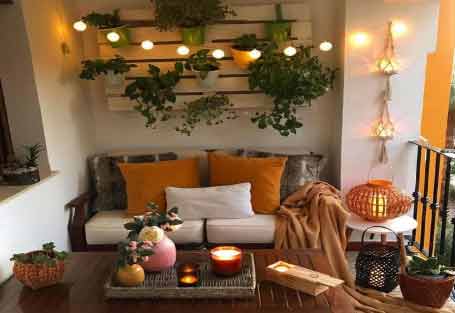 Görselde, beyaz duvarında saksı çiçekleri olan geniş bir balkon var.