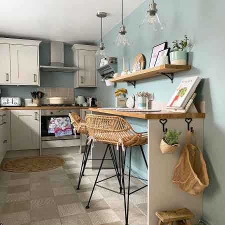 Küçük Oda Dekorasyonu – Mutfak. Görselde, dolapları, duvara monteli dar masa ve rafları ile dekore edilmiş kullanışlı küçük bir mutfak var.