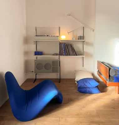 Küçük Odalar için Mobilya Seçimi – Raflı Masa. Görseldeki küçük odada, konforlu bir yer koltuğu ve minimalist tarzda raflı bir masa var.