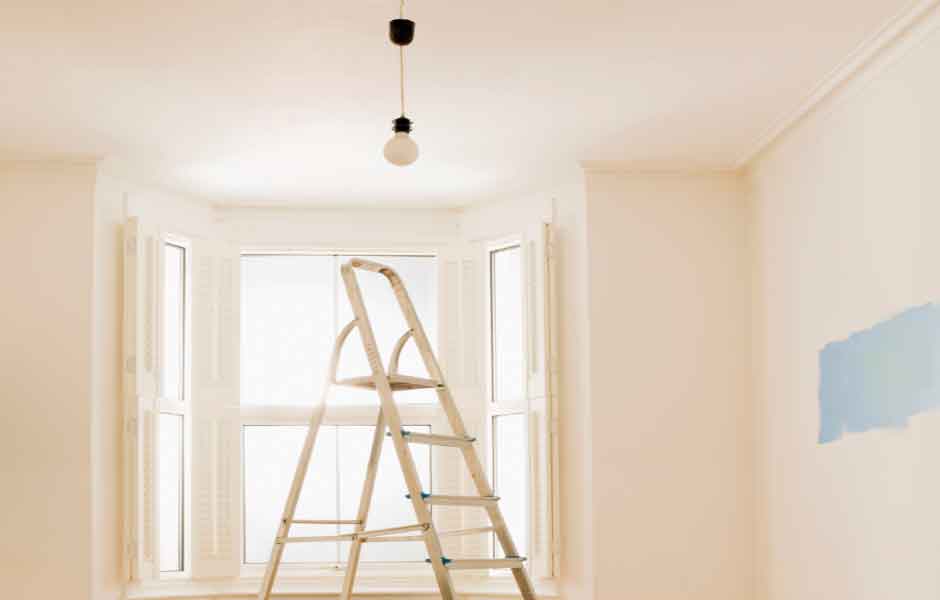 Tavan nasıl boyanır konusu için kullanılan görseldeki oturma odasında, boyacı ustası tarafından boyanmayı bekleyen rutubetli bir tavan ve katlanır bir merdiven var.