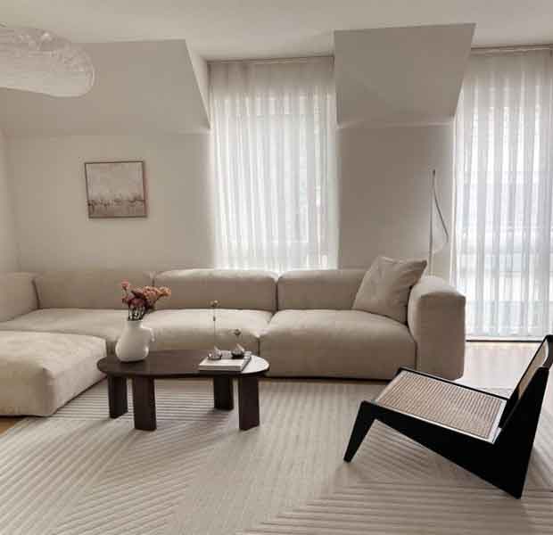 1+1 ev dekorasyonu örnekleri için kullanılan görselde, duvarları beyaz olan ve içerisinde krem rengi mobilyaların olduğu aydınlık bir oda var.