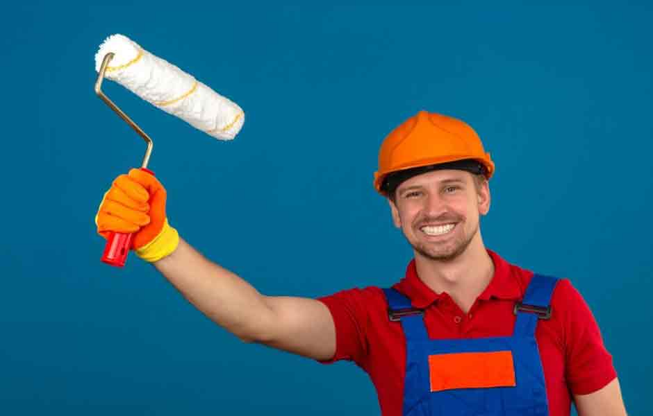 Profesyonel boyacı ustası nasıl olunur sorusu için kullandığımız görselde, iş kıyafeti, başlık ve eldiven giymiş erkek boyacı, iş sağlığı tedbirlerine uyduğunu gösteriyor.